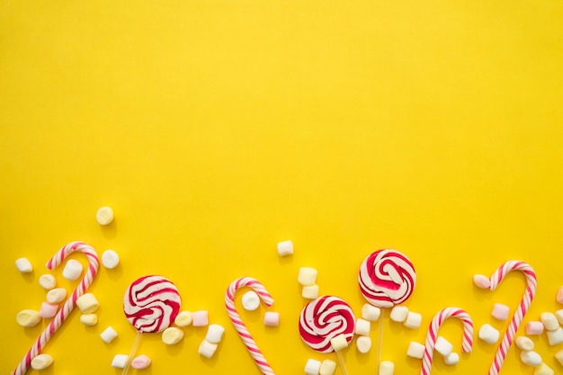 Yellow background with candy canes, lollipops and marshmallows