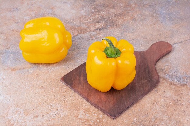 Yellow bell peppers on a wooden platter.