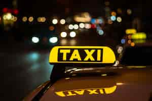 Free photo yellow and black sign of taxi placed on top of a car at night