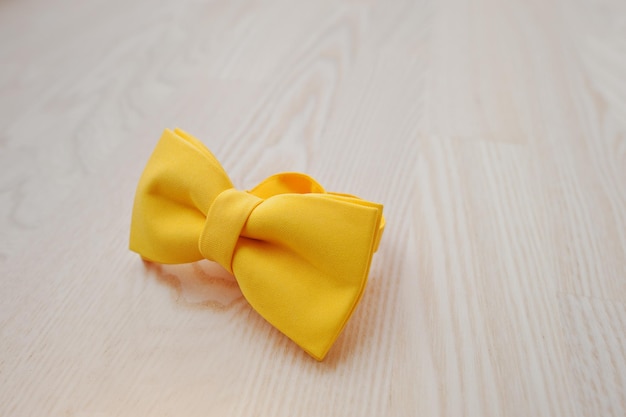 Free photo yellow bow tie on light wooden background