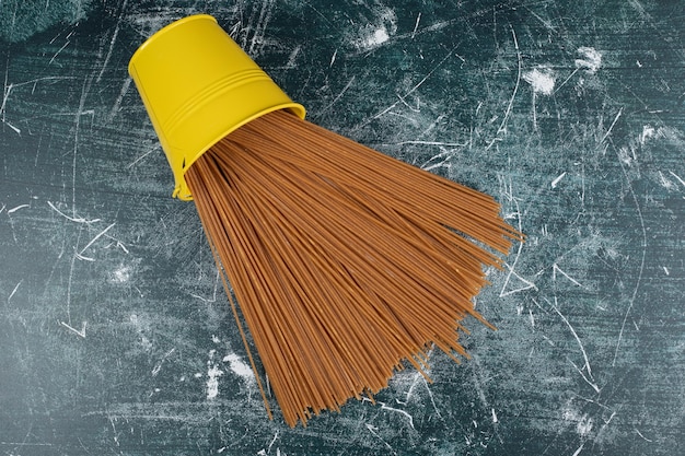 Free Photo yellow bucket full of raw pasta on marble background. high quality photo