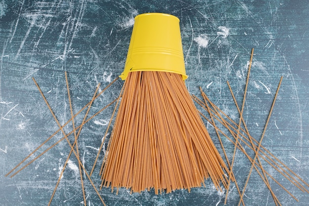 Free Photo yellow bucket full of raw pasta on marble background. high quality photo