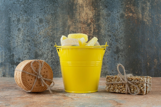 Free Photo a yellow bucket of marmalade with cookies and peanut brittles