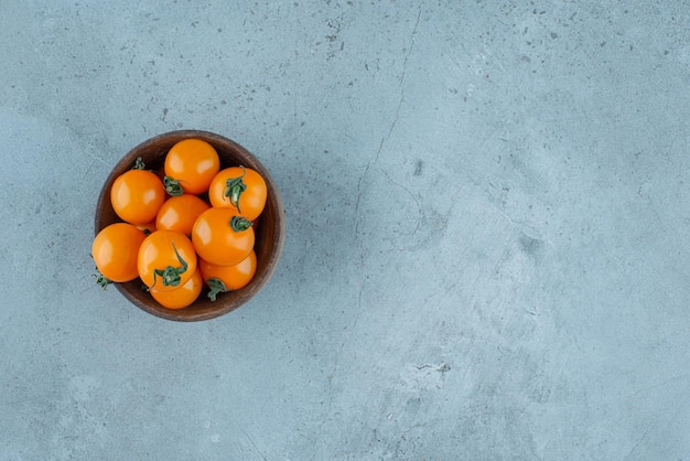 Yellow cherry tomatoes in a wooden cup.