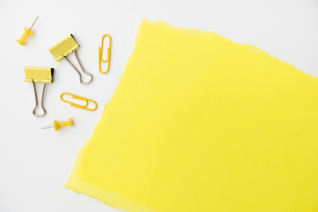 Free photo yellow craft paper with paperclip and pushpin on white backdrop