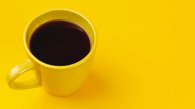 Yellow cup of coffee on a yellow background