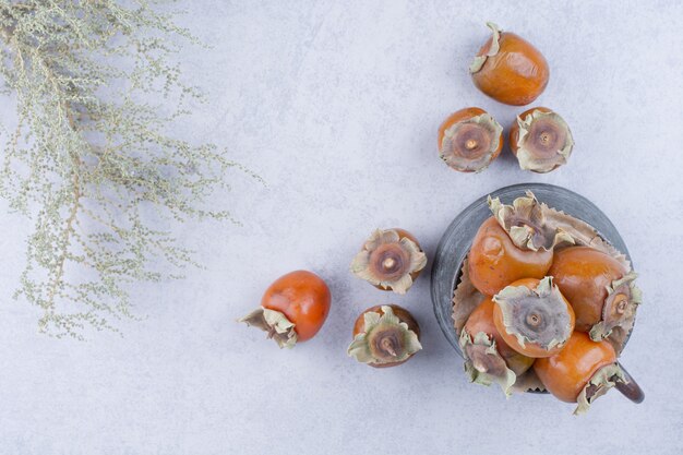 Yellow date plums in a metallic pot on grey.