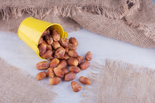 Yellow dry dates in a cup on concrete surface