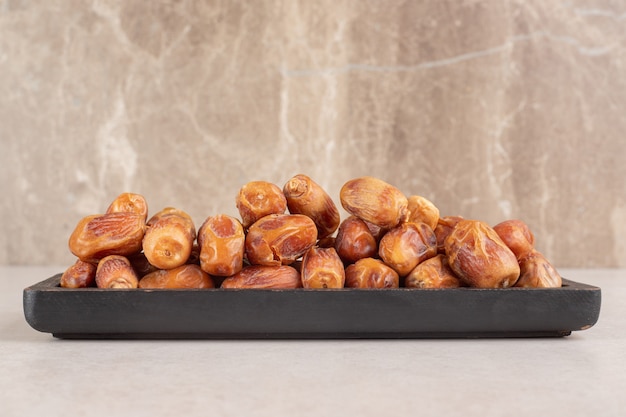 Yellow dry dates isolated on a wooden platter.