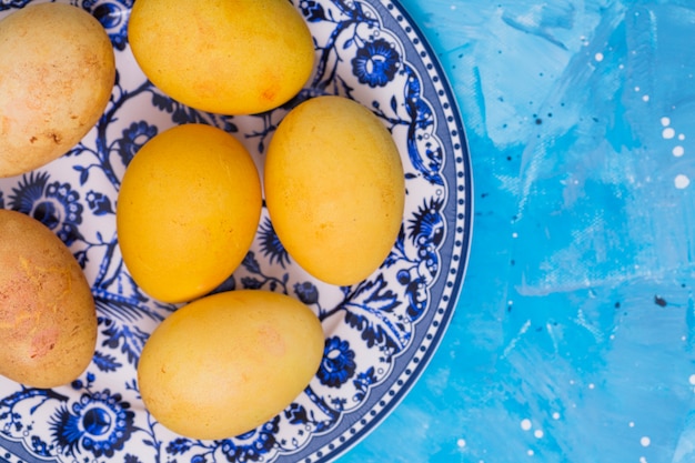 Yellow Easter eggs on plate on blue table