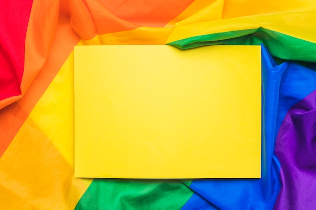 Yellow empty paper sheet on crumpled LGBT flag