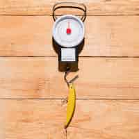 Free photo yellow fishing bait hanging on measuring scale over the wooden desk