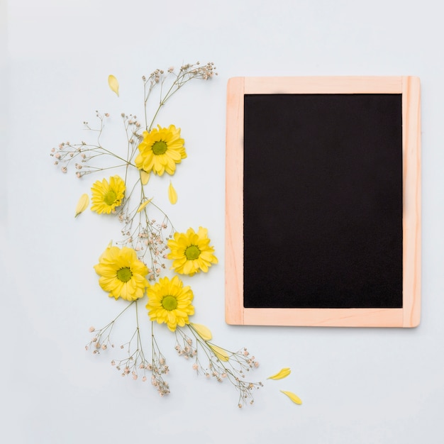 Free photo yellow flower decoration near the wooden blank slate on white background