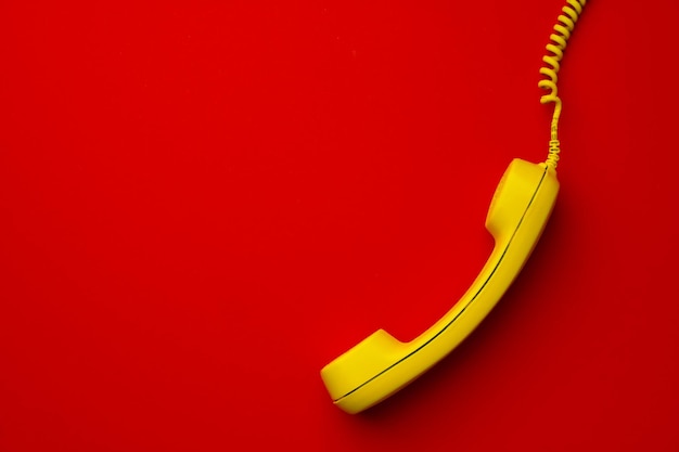 Free Photo yellow landline phone on red background top view