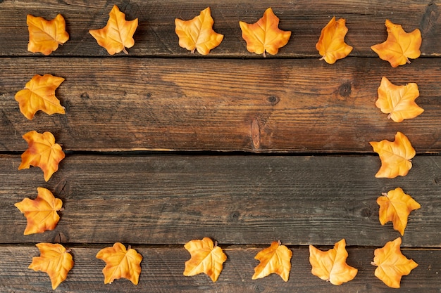 Yellow leaves frame on wooden background with copy space