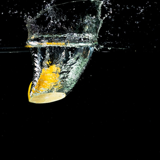 Free Photo yellow lemon falling into water splash