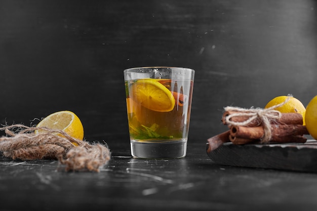 Yellow lemons on a black surface with a glass of glintwine. 