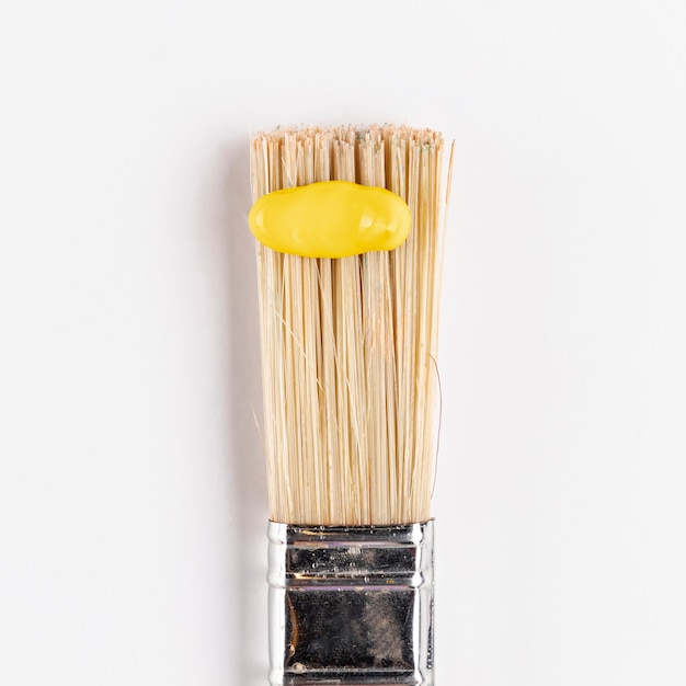 Free photo yellow paint on brush with white background