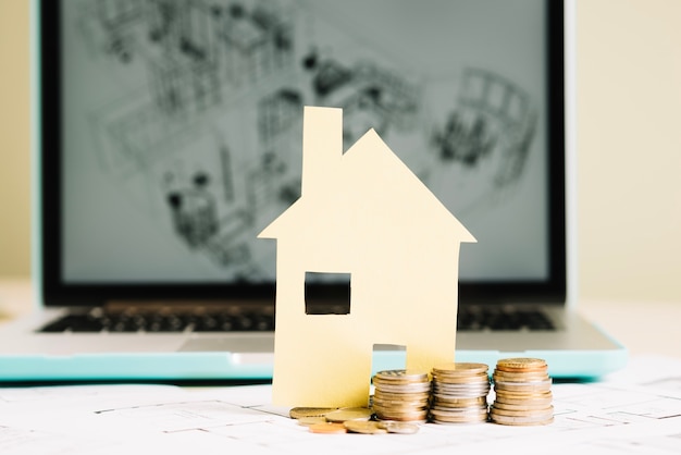 Free photo yellow paper house and coins at laptop