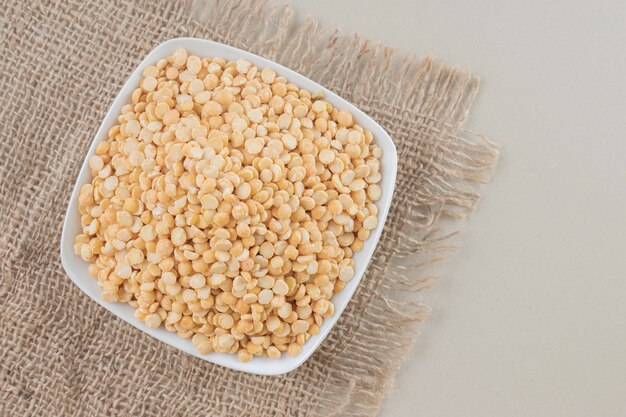 Yellow pea beans in a ceramic cup on concrete.