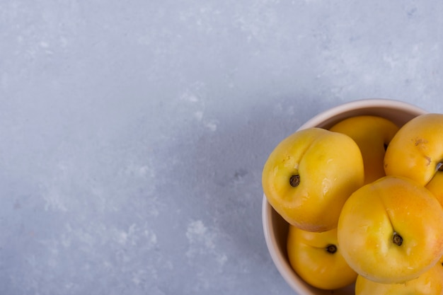 Yellow peaches in a white ceramic bowl in the bottom corner