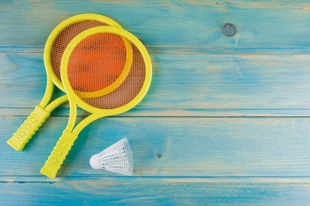 Free Photo yellow plastic tennis racket and shuttlecock on blue yellow turquoise desk