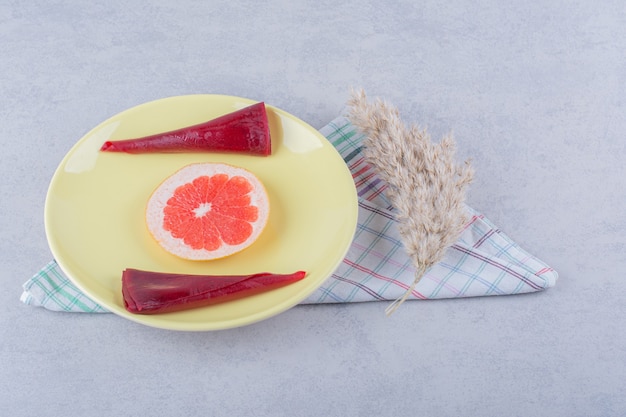 Yellow plate of dry fruit pulps and grapefruit on stone table. 