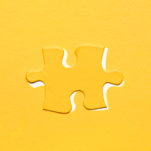 Free photo yellow puzzle piece over colored backdrop