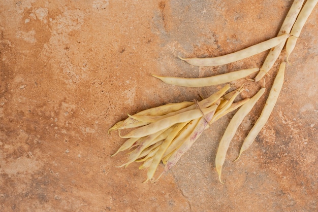 Yellow raw beans on orange surface.