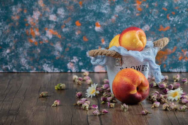 Yellow red peaches out of a blue metallic bucket. 