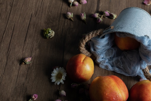 Free photo yellow red peaches out of a blue metallic bucket.