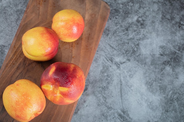 Yellow red peaches on wooden board.