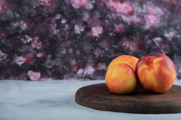 Yellow red peaches on wooden board.