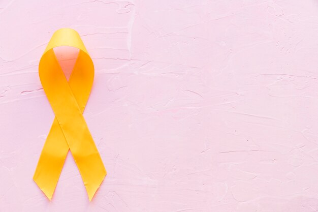 Yellow ribbon symbolic color for sarcoma bone cancer on pink backdrop