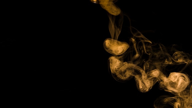 Free photo yellow smoke curl on black background with copy space for writing the text