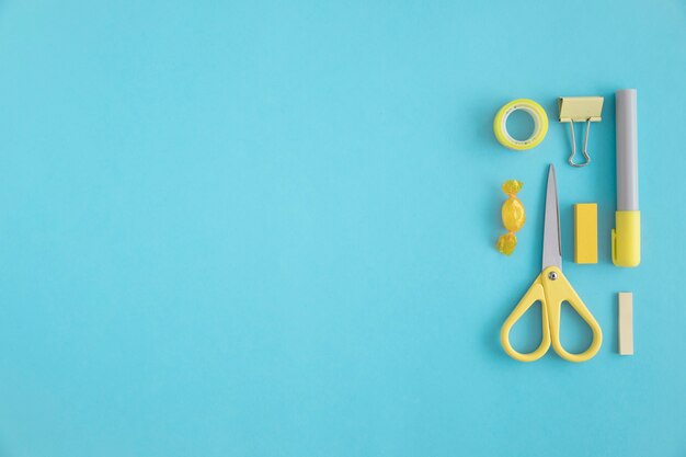 Yellow stationery and candies on blue backdrop