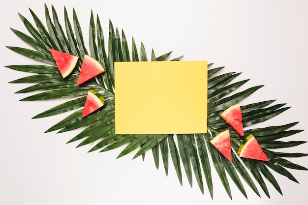 Free Photo yellow sticky note and sliced red watermelon at palm leaf