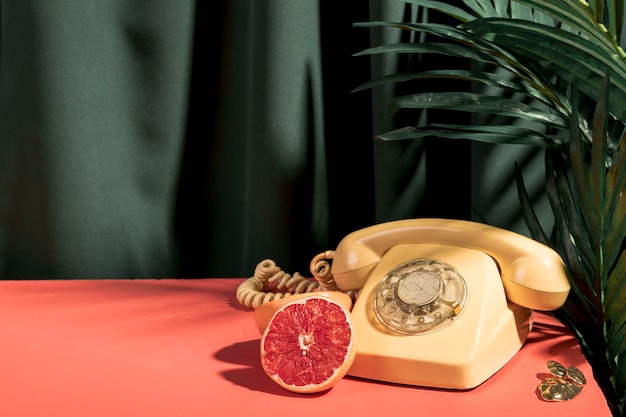 Yellow telephone next to grapefruit on table