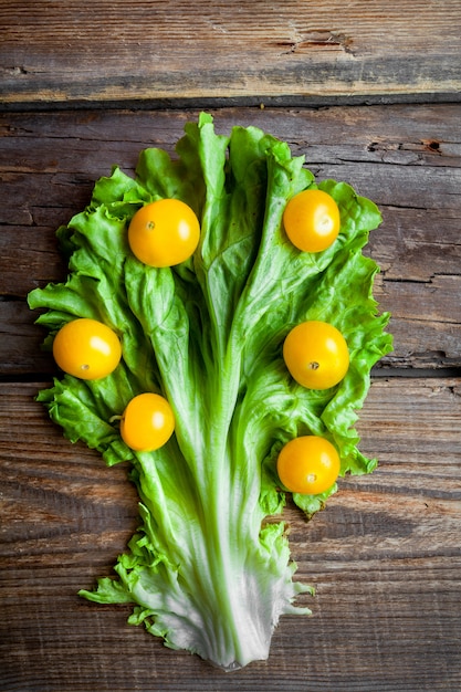 Yellow tomatoes on a lettuce on a dark wooden background. top view.