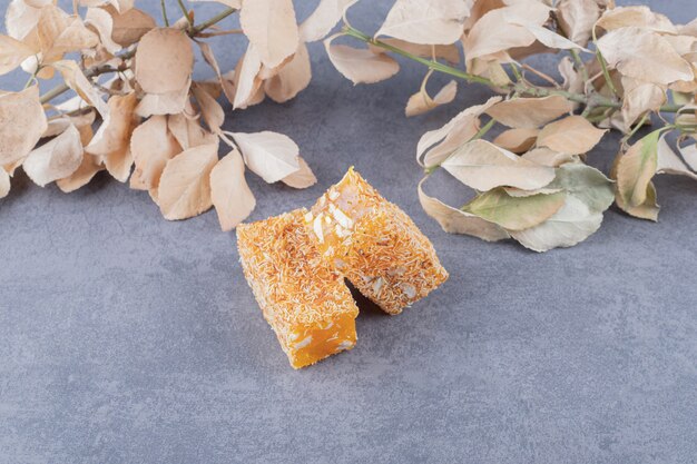 Yellow traditional turkish delight with peanuts and decorative dry leaves.