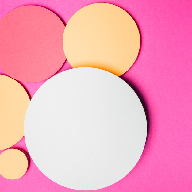 Free photo yellow; white and red round paper circle frame on pink background