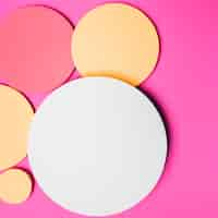 Free photo yellow; white and red round paper circle frame on pink background