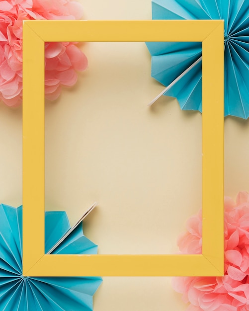 Yellow wooden border photo frame on paper flower over beige backdrop