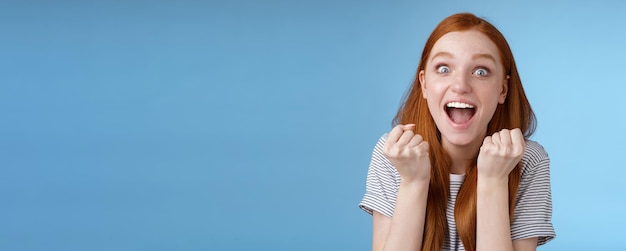 Free photo yes awesome news great attractive surprised redhead girl cheering happy clench fists yelling yeah accomplish goal wide eyes excited celebrating win lottery triumphing joyfully blue background