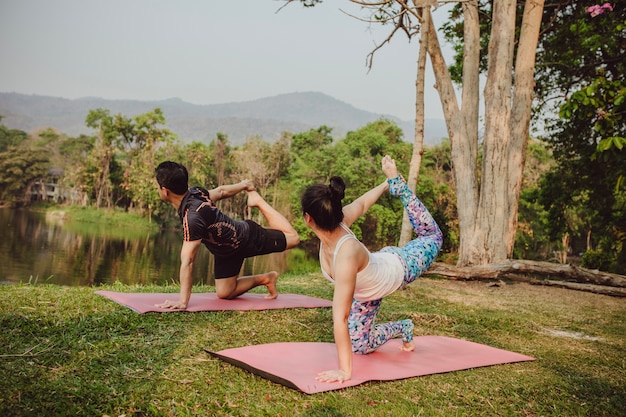 Yoga lovers stretching next to the lake