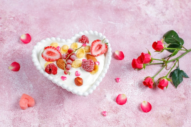 Yogurt with corn flakes and berries in a heart-shaped bowl.