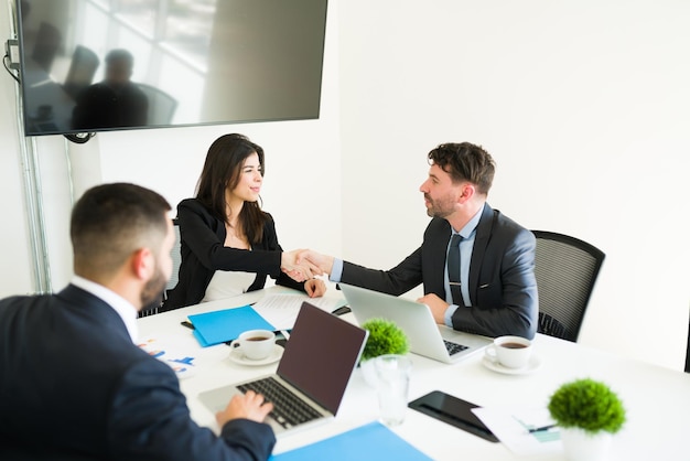 You have a deal. Attractive sales representative shaking hands with a handsome executive after signing a business contract during a meeting