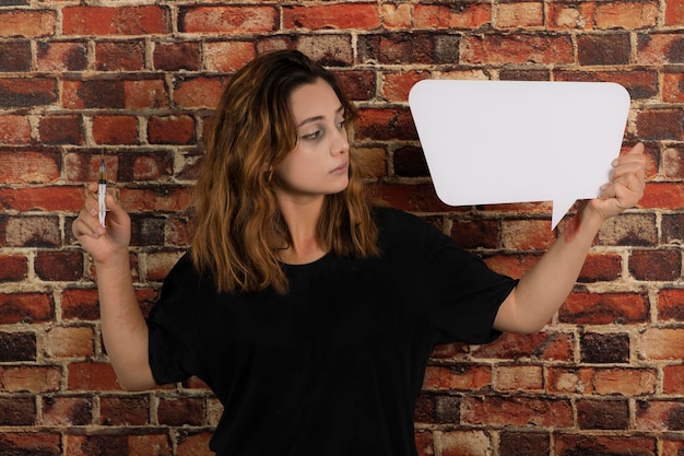 Young addicted the girl holding injection and white idea boat. Girl looking at idea board. High quality photo