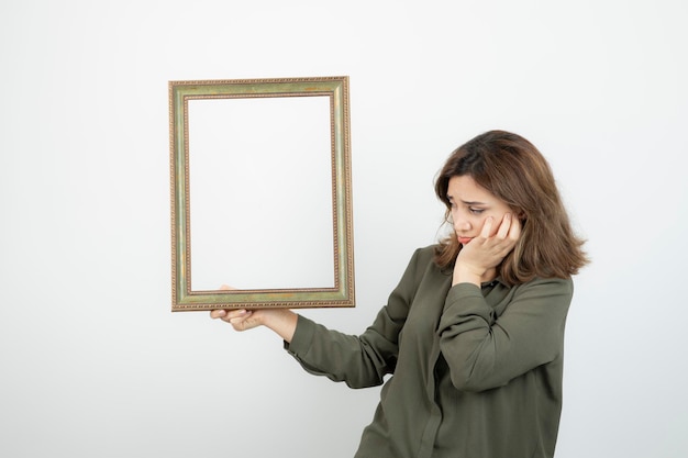 Free Photo young adorable female model holding empty wooden frame. high quality photo