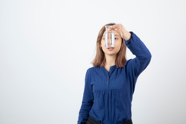 young adorable girl looking at glass of water on white.